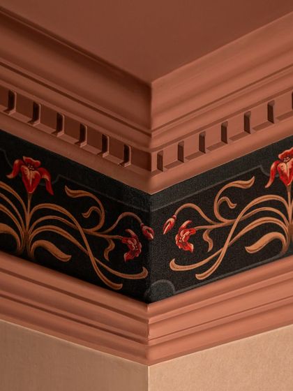 The finished custom cornice in Zone Three. We designed a bespoke wallpaper border with a floral motif to wrap around the cornice, creating a bold, continuous edge that frames the maximalist space and ties the color palette together.