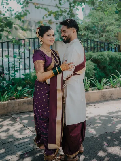 A full-length shot of a couple in coordinated purple and white Maharashtrian outfits. This photo captures the elegance of their traditional attire and their happy, relaxed posture during their wedding shoot in Mumbai.