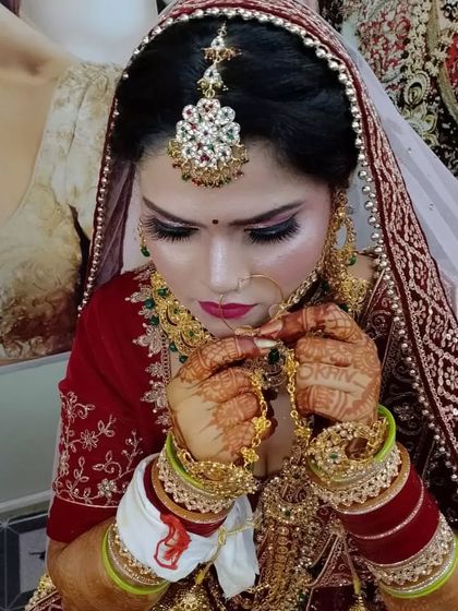 A close-up shot of a bride on her wedding day. This image captures the details of the eye makeup, the perfectly placed bindi, and the intricate henna design.