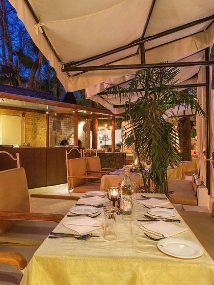 An outdoor table set for a larger group, offering a relaxed yet elegant setting for a shared meal under the evening sky.