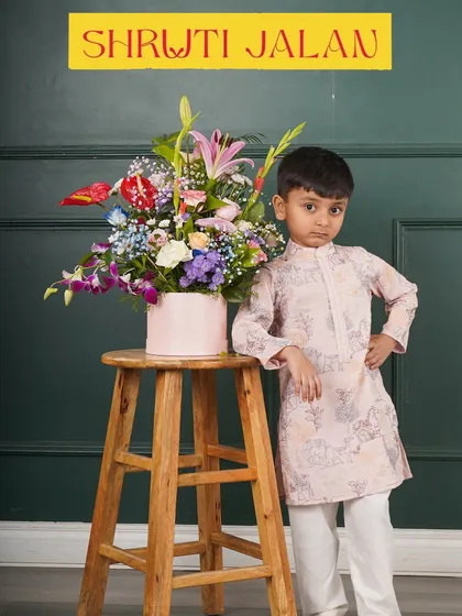 Little man, big style. This boy is posing in a pink printed kurta, looking sharp and ready for a family photo.