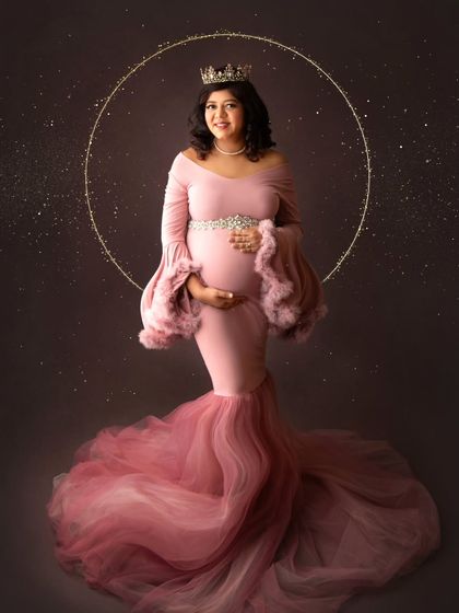 A truly magical fine-art portrait. This mom-to-be wears a stunning pink mermaid-style gown and a crown, framed by a halo of golden light.