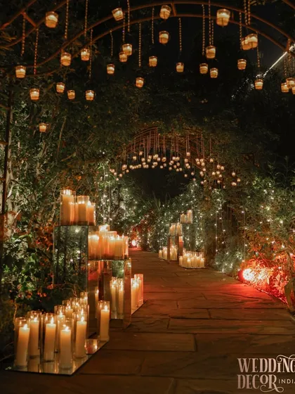 Imagine walking into your celebration through a pathway of pure magic. We created this ethereal walkway with hundreds of candles in glass hurricanes and hanging lanterns, casting a warm, romantic glow that promises an evening of unforgettable moments.