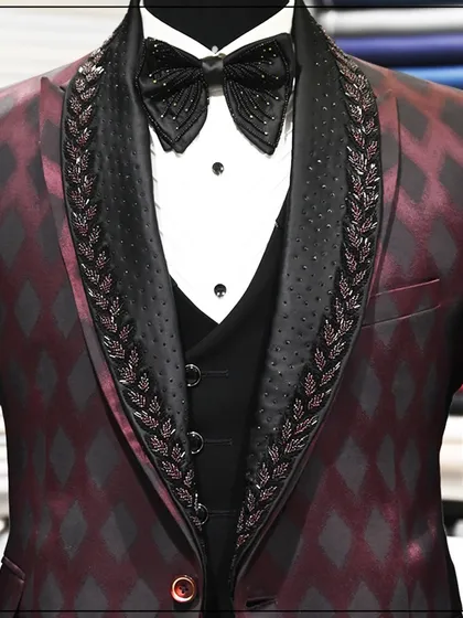 A detailed shot of the burgundy diamond-patterned tuxedo, focusing on the texture of the fabric and the hand-beaded lapels.