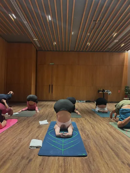 Students practicing Yoganidrasana, or yogic sleep pose. This advanced posture requires immense hip flexibility and a calm, surrendered mind.