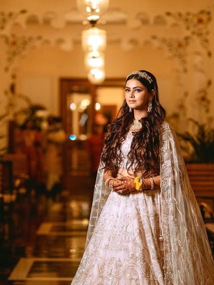 The bride looking regal in the beautifully lit, traditional interiors of the Udaipur venue.