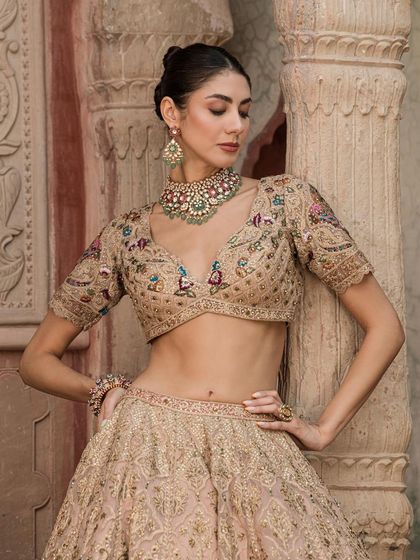 A model poses in a beautiful beige lehenga, wearing a navratan-style choker with multiple colored stones. A versatile piece for any festive occasion.