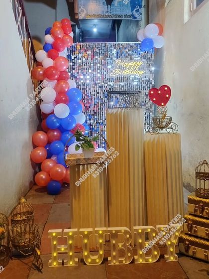 A compact yet stylish birthday setup for a husband, featuring a silver sequin wall and marquee letters in a narrow space.