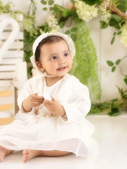 An angelic portrait in all white. The soft lighting and green foliage create a fresh, natural feel in the studio.