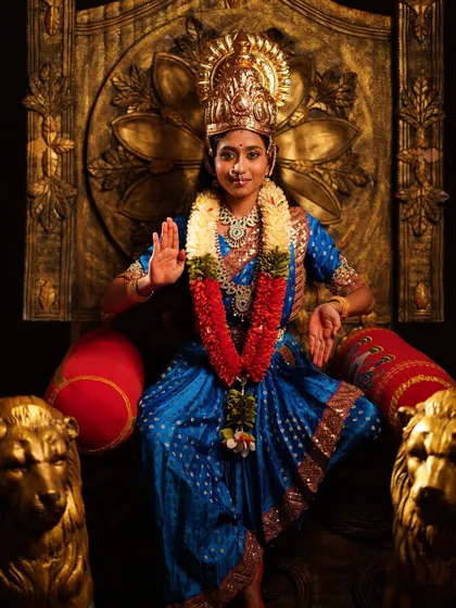 A beautiful Devi costume, available for both kids and adults. This shot features a model in a blue silk saree, adorned with a crown and garlands on a golden throne.