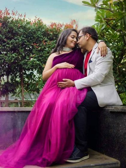 An intimate couple's moment during their maternity shoot. The one-shoulder design of this magenta gown adds a modern touch to the romantic portrait.