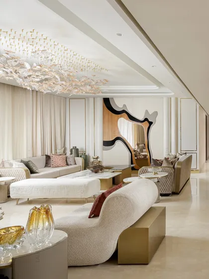 Here, we played with geometry and form. A sculptural wall mirror with wood and black accents serves as a backdrop for a living space filled with quilted sofas, a textured ottoman, and nested side tables.