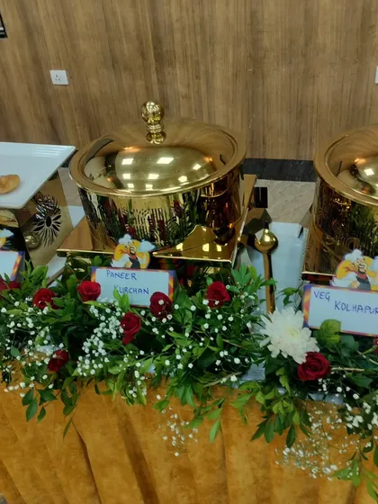 A close-up of my buffet setup, showing labeled main course dishes like Paneer Kurchan and Veg Kolhapuri served in polished golden warmers.