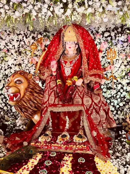An intricate and devotional display featuring a beautifully adorned idol of the goddess, set against a dense wall of white flowers. This showcases our expertise in creating detailed thematic decor for religious events.