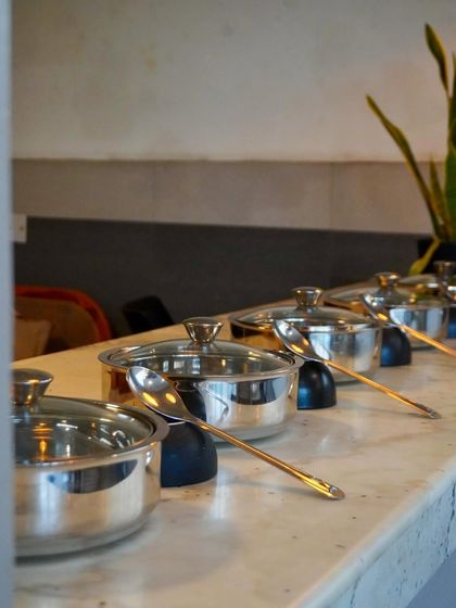 A clean and professional buffet setup for a house party. We provide all the necessary equipment, including these stylish steel serving dishes, to ensure the food stays hot and looks great.