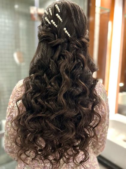 A back view of the pearl-adorned half-up style, showing the intricate braid and curl pattern.
