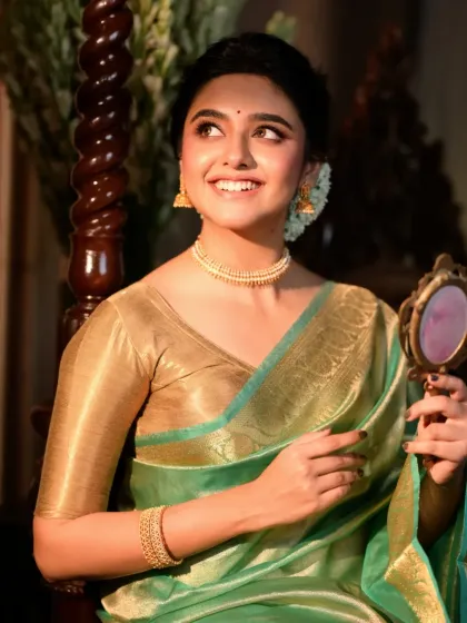 A joyful portrait of a model looking into a handheld mirror. The warm light and her bright smile capture a moment of happy anticipation and self-appreciation.