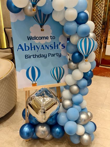 A personalized welcome sign on an easel, decorated with a balloon garland to match the Hot Air Balloon theme.