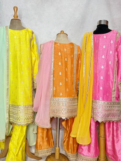 The Pimmo kurta set is a festive favorite. Available in bright yellow, orange, and pink, this sharara-style set is made from shimmering fabric with intricate gota patti work.