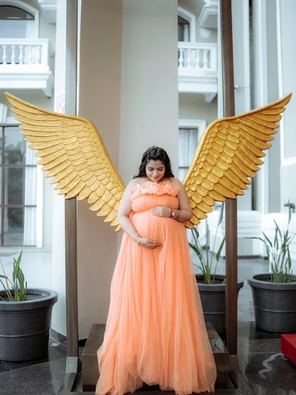 Feel like an angel in our peach Isabella gown. The color is warm and flattering, and this shot with the golden wings prop adds a touch of whimsical magic.