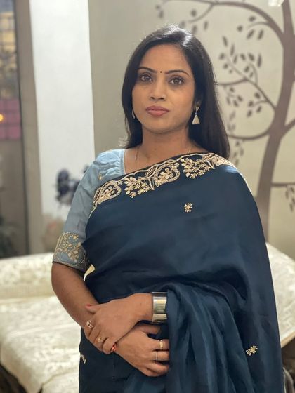 A close-up of the client in the deep teal blue saree, showing the delicate embroidery and her simple, elegant jewellery.