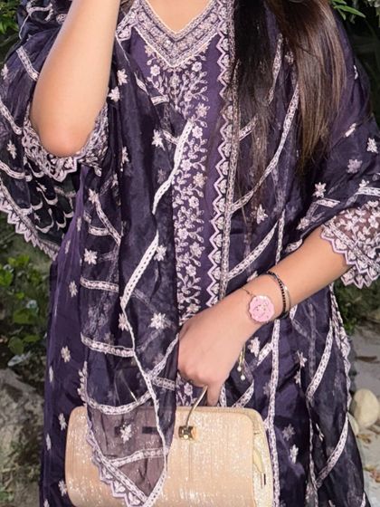 A close-up of the outfit, focusing on the intricate embroidery and the elegant clutch.