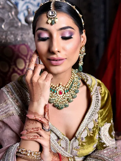 A close-up of this gorgeous bride. Her makeup features a stunning purple and pink smokey eye, which beautifully complements her olive and pink lehenga.