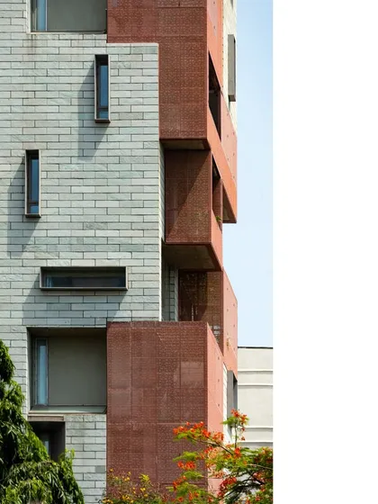 A close-up of the J-House facade reveals a playful pattern of openings and the texture of its materials. The western edge features deep, shaded verandahs with operable screens to mediate the harsh sun and monsoon while framing views of the sea.
