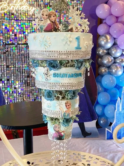 This Frozen-themed chandelier cake was a magical centerpiece for a first birthday party. The multi-tiered design incorporates characters from the movie, sparkling silver details, and crystal-like hanging elements to bring the winter wonderland theme to life.