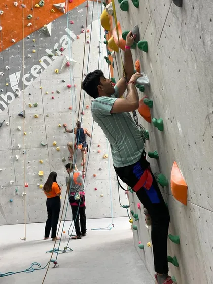 A climber chalks up before starting a route, with his belayer ready on the ground.