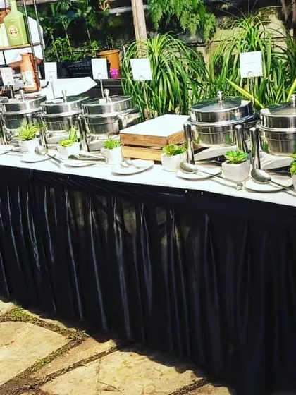A clean and green buffet theme for an outdoor event. The combination of stainless steel chafing dishes and natural plant decor creates a fresh and modern look.
