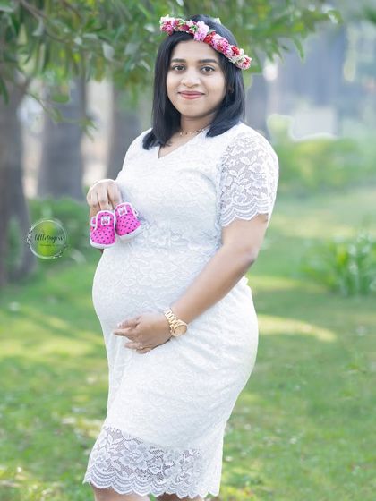 A sweet and simple portrait in a white lace dress. Holding the little pink shoes, this mom-to-be radiates happiness and anticipation for her baby girl.