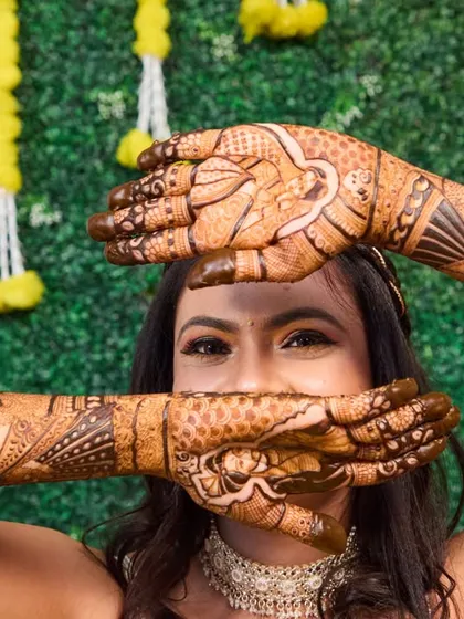 A fun and playful mehendi portrait. This pose allows the bride to show off her beautiful henna in a creative way, highlighting the detailed artwork.