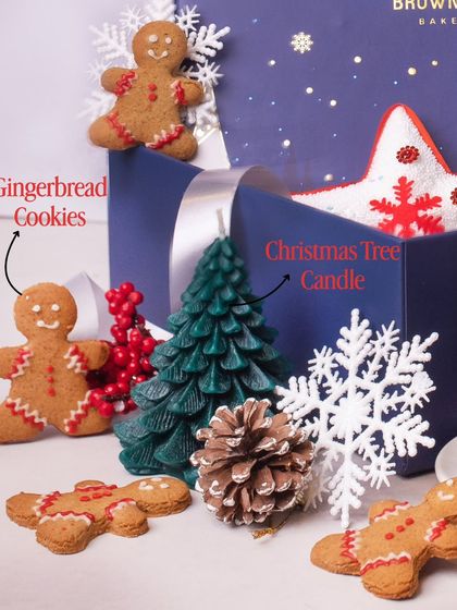 A close-up of the festive elements in our Christmas hampers. This image highlights our adorable, hand-decorated gingerbread cookies and a Christmas tree candle, which adds a non-edible festive touch to the gift box.