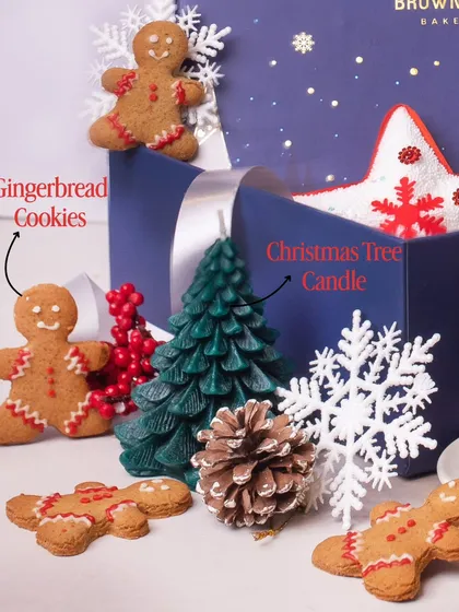 A close-up of the festive elements in our Christmas hampers. This image highlights our adorable, hand-decorated gingerbread cookies and a Christmas tree candle, which adds a non-edible festive touch to the gift box.