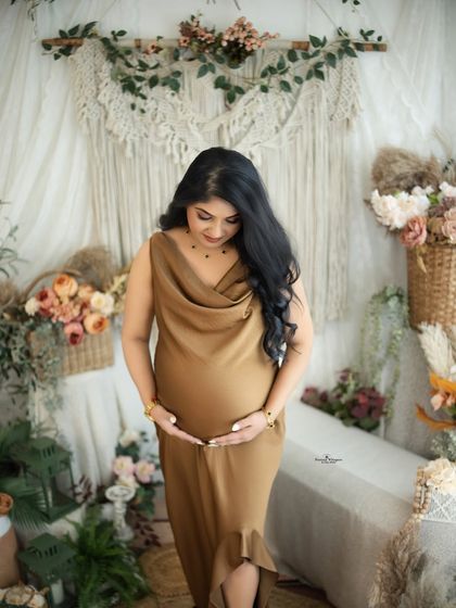 A graceful solo portrait of a mother-to-be in a stylish bronze-colored satin gown. The rich color and soft fabric look beautiful in our earthy boho setup.