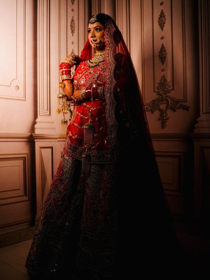 A full-length shot capturing the grandeur of her red bridal lehenga and the long, flowing veil.