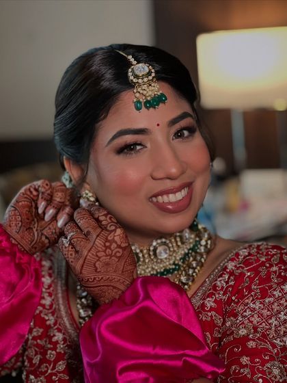 A happy smile from my bride Hiral as she puts on her earrings. I used warm tones and a soft contour to enhance her features for her Pheras.