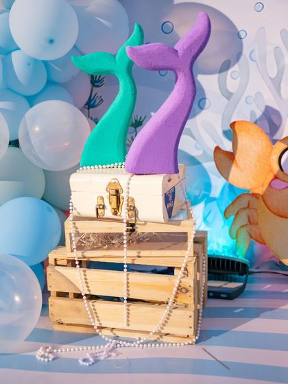 A close-up of some of the decor props, including mermaid tails and pearl necklaces draped over wooden crates. These small touches create a rich, layered look.