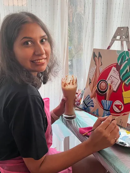 A participant enjoying a cold coffee while painting at a cafe workshop. The combination of art and cafe treats makes for a perfect afternoon.