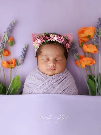 Dreaming in a field of flowers. This artistic setup places a peacefully sleeping newborn among lavender and poppy props, creating a beautiful, colorful, and imaginative portrait.