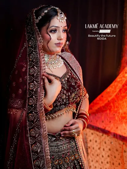 A contemporary bridal look with a deep maroon lehenga. The focus is on creating a soft, romantic feel with glowing makeup and elegant hairstyling, perfect for an evening wedding.