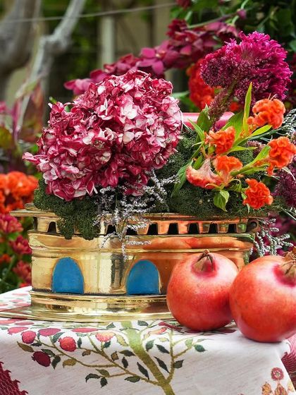 A close-up of a brass lantern and fresh pomegranates on a custom-printed table runner, showcasing the rich colors and textures of the theme.