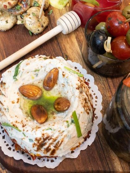 A close-up of a creamy labneh or cheese dip, topped with toasted almonds and drizzled with herb-infused oil.