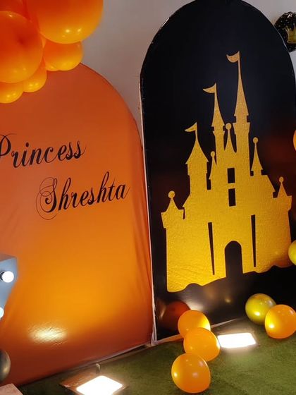 A unique princess-themed seventh birthday with a black and orange color scheme. The setup features a castle silhouette backdrop and a large light-up number '7'.