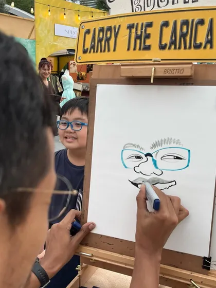 A close-up of the action. A guest watches intently as his caricature is created at a Dubai event.