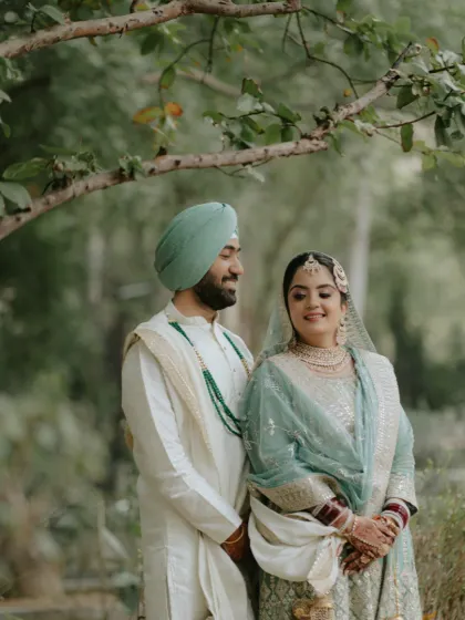 A romantic shot of the couple under the trees. Her makeup is soft and natural, perfectly fitting the outdoor setting.