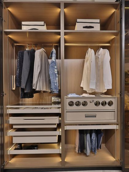 A look inside a highly organized wardrobe, showcasing pull-out drawers, dedicated hanging space for shirts and trousers, and a special compartment for accessories. Every item has its place.