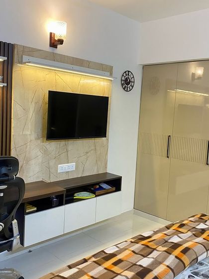 This bedroom features a combined study table and TV unit, a great way to save space. The design uses wood and white finishes for a clean look.