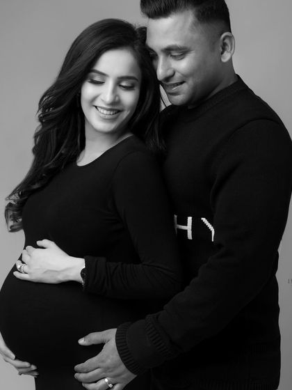 An intimate black and white portrait of an expecting couple. Their gentle embrace and soft smiles convey a world of love and anticipation.